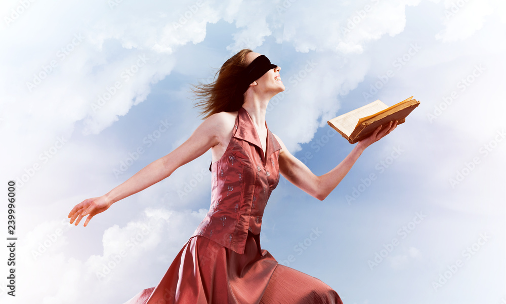 Girl against cloudy sky with opened book in palm as idea for knowledge