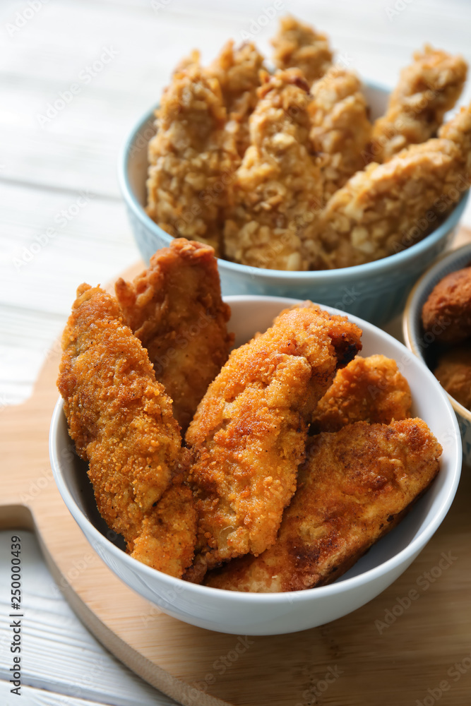 Bowls with tasty nuggets on white table