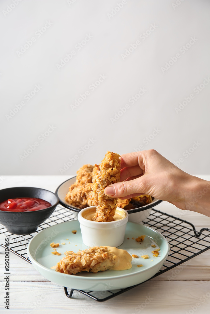 Woman eating tasty nuggets with sauce