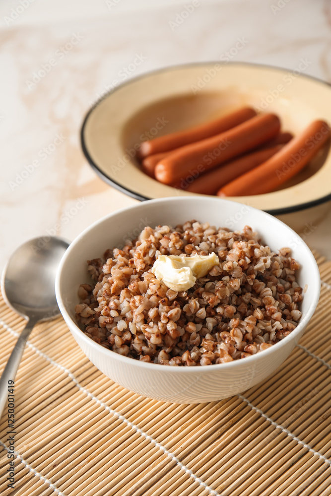 Bowl with tasty boiled buckwheat on table