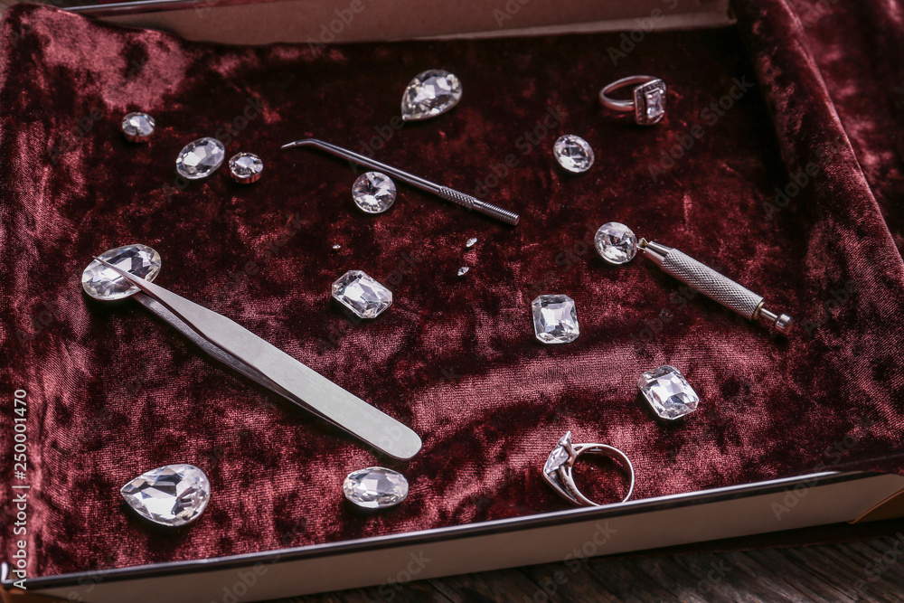 Box with precious stones and jewelers tools on table