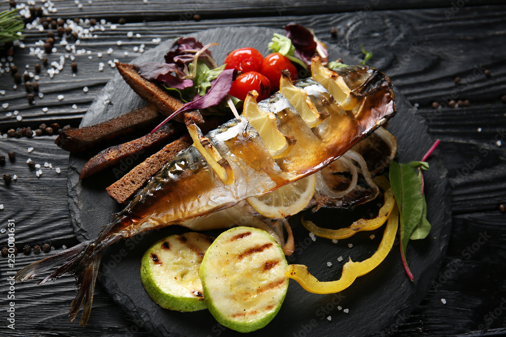 Grilled mackerel fish with garnish on slate plate