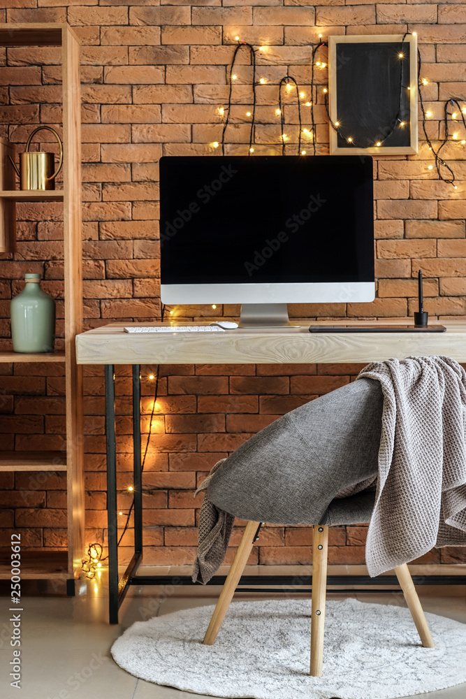 Interior of modern room with comfortable workplace near brick wall