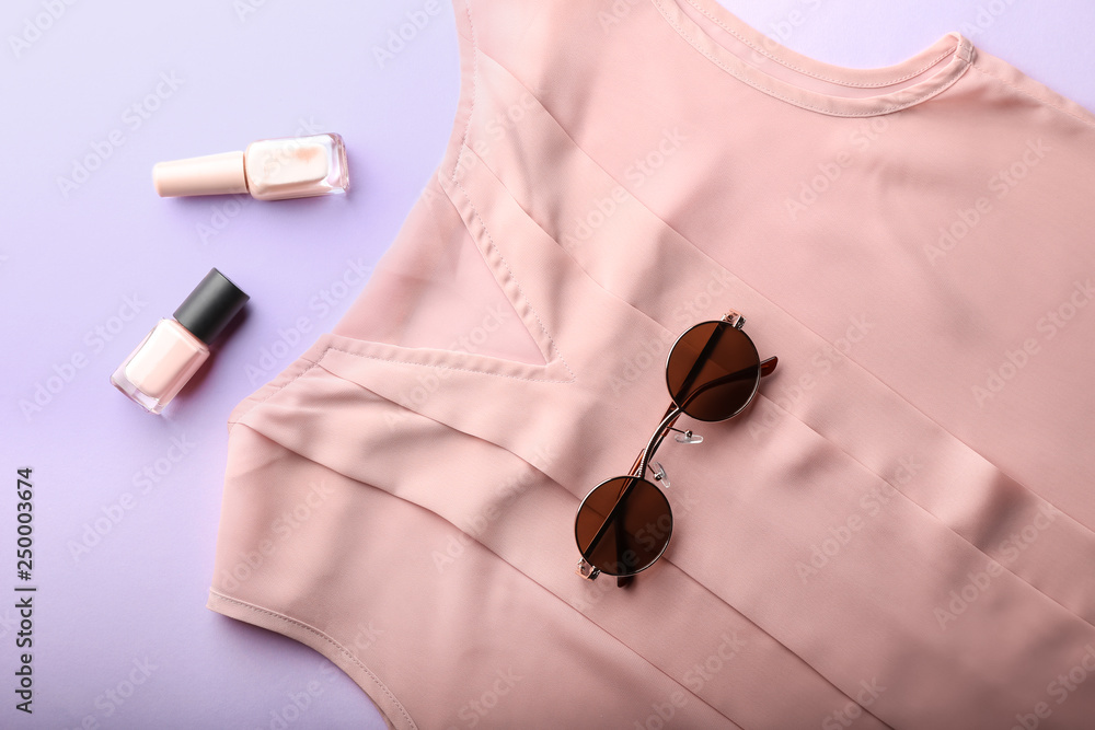 Female clothes, sunglasses and cosmetics on color background