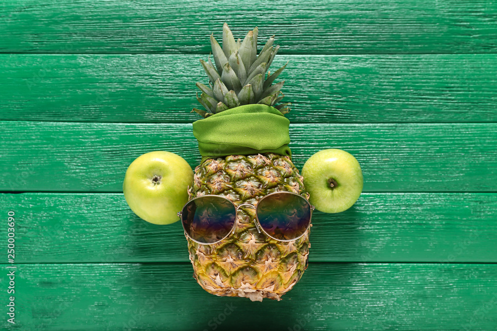 Creative composition with pineapple and sunglasses on color wooden background