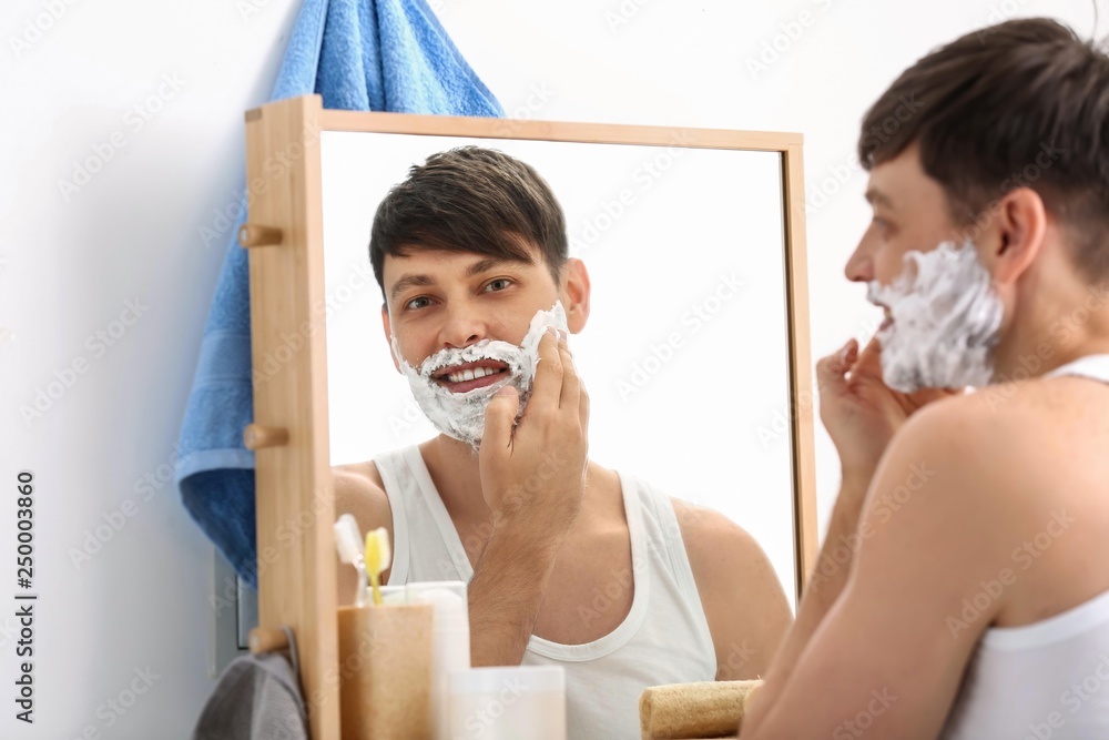 Handsome man shaving in bathroom