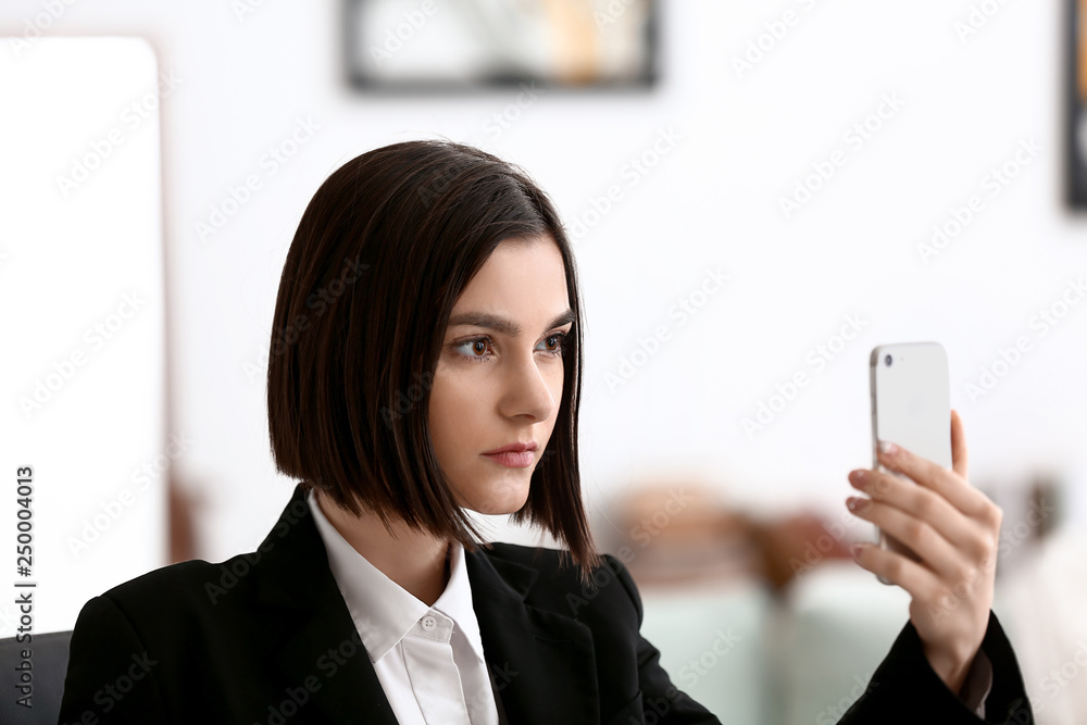 Young woman taking selfie with mobile phone in office