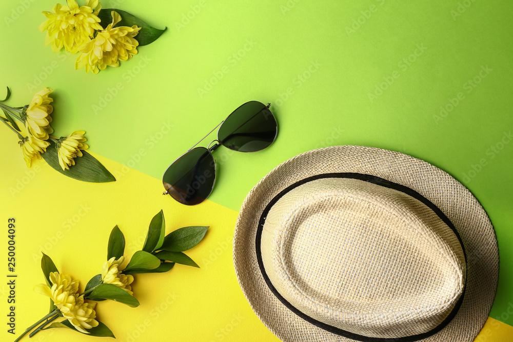 Hat, sunglasses and flowers on color background