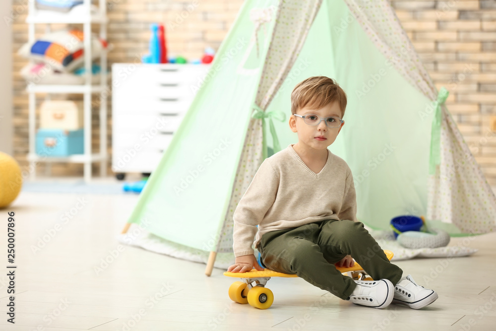 Portrait of cute little boy with skateboard at home