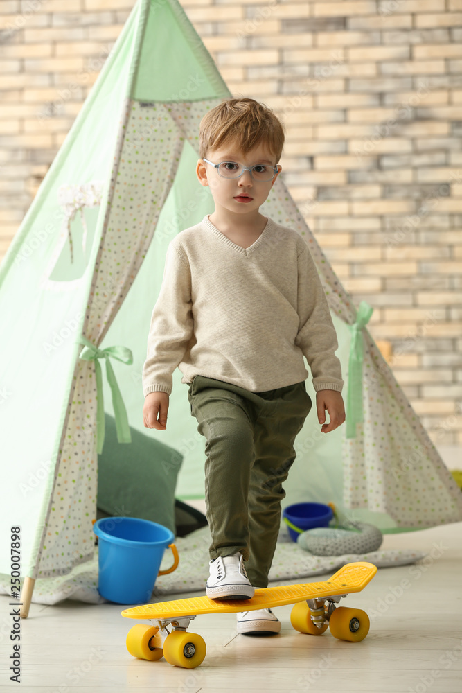 Portrait of cute little boy with skateboard at home