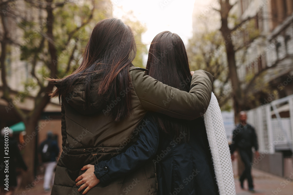 两名妇女走在街上的后视图