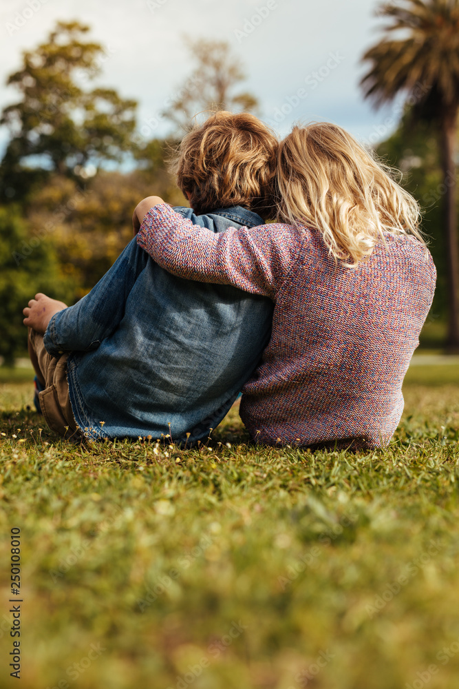 Small brother and sister sitting at park