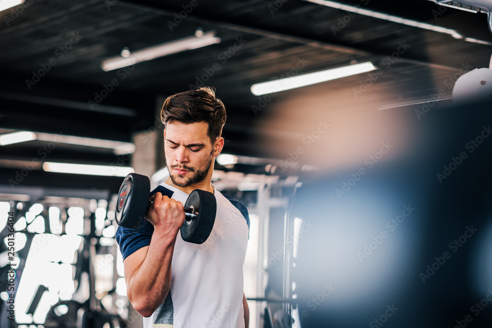 Young man in sportswear exercising with weights.