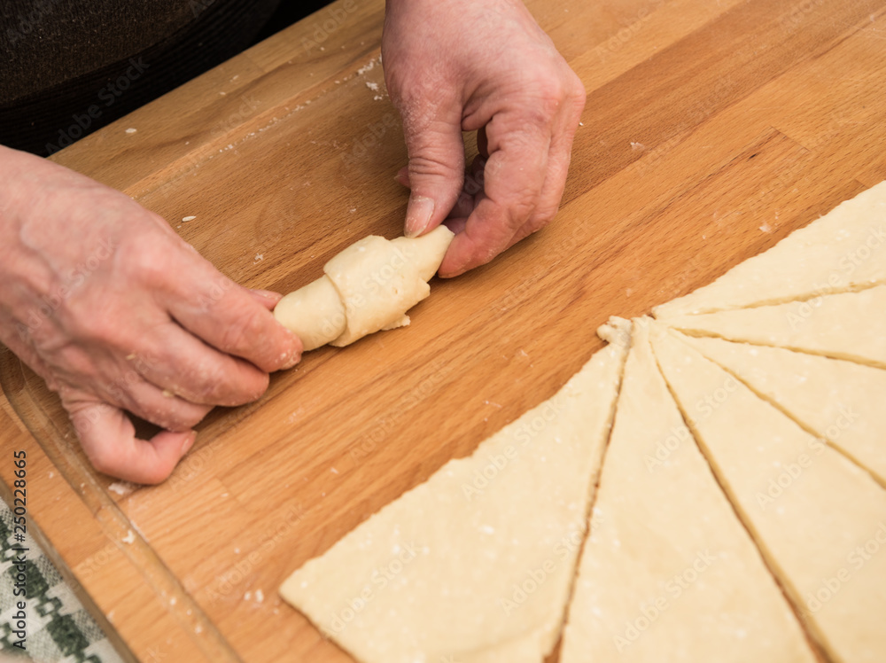  Woman rolling dough into rolls for further baking