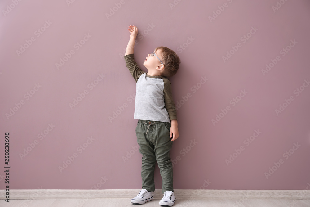 Portrait of cute little boy near color wall