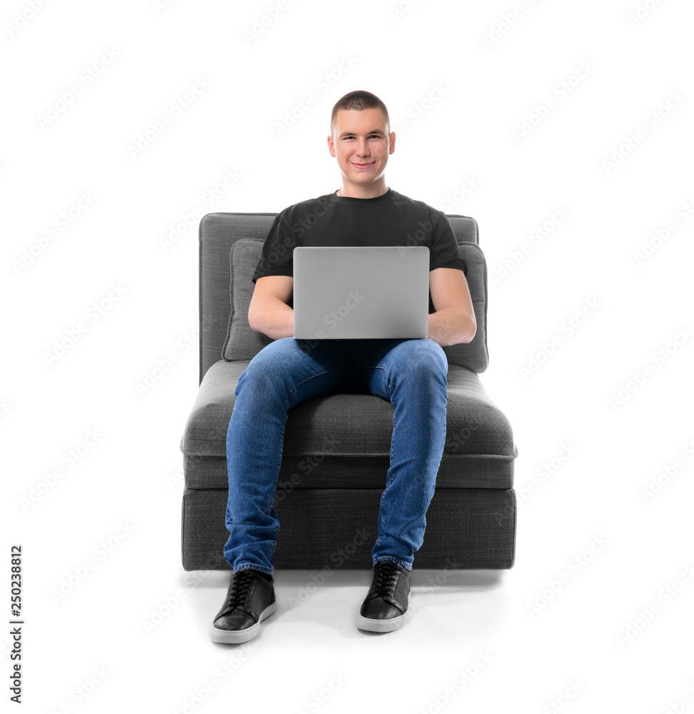 Young man with laptop sitting in armchair against white background