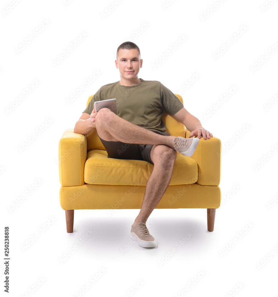 Young man with tablet computer sitting in armchair against white background