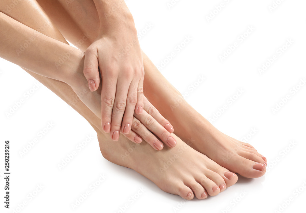 Legs and hands of young woman with beautiful pedicure and manicure on white background