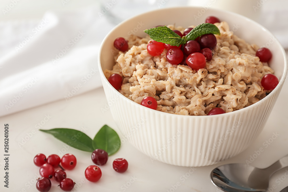 Bowl with tasty oatmeal on white table