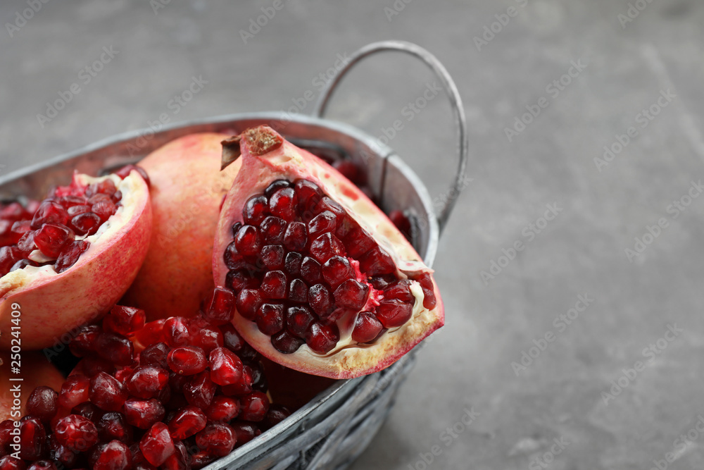 Basket with ripe pomegranates on grey background