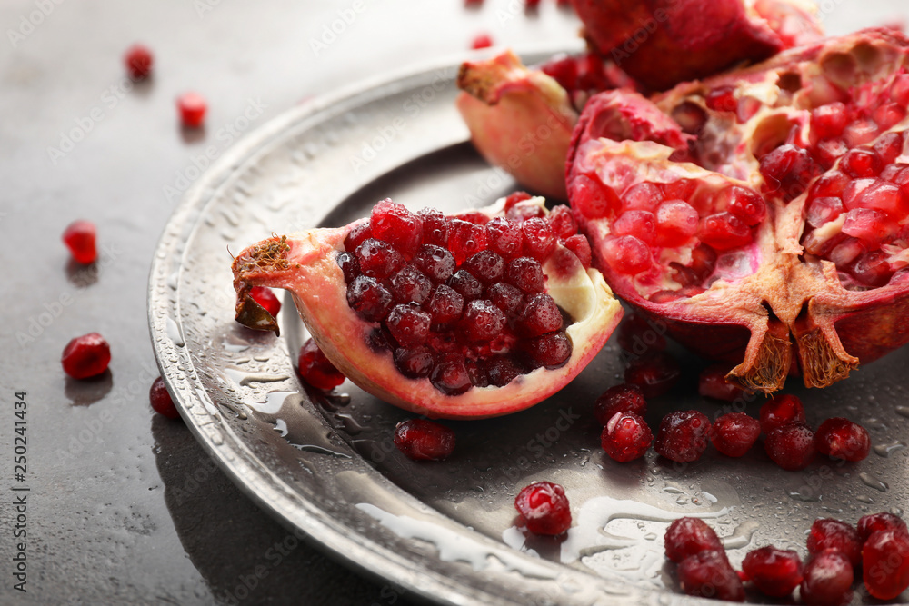 Plate with pieces of ripe pomegranate on table, closeup