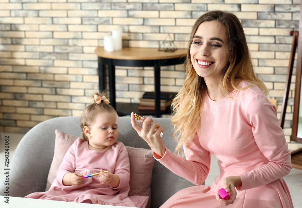 Young woman with her cute little daughter playing with cosmetics at home