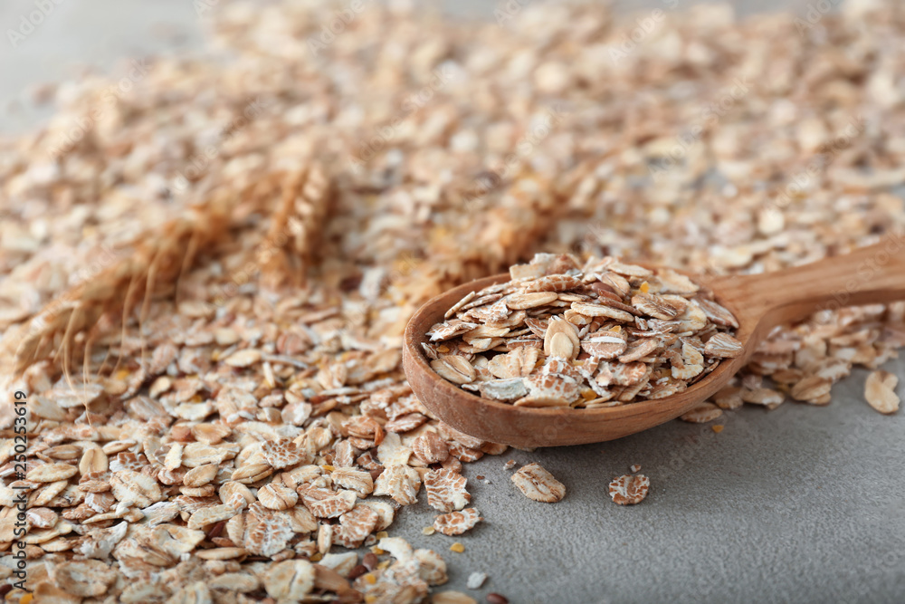 Spoon with oat flakes on grey table