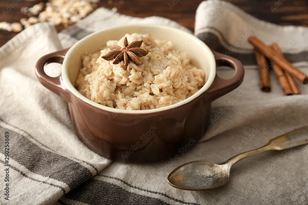 Pot with tasty oatmeal on table