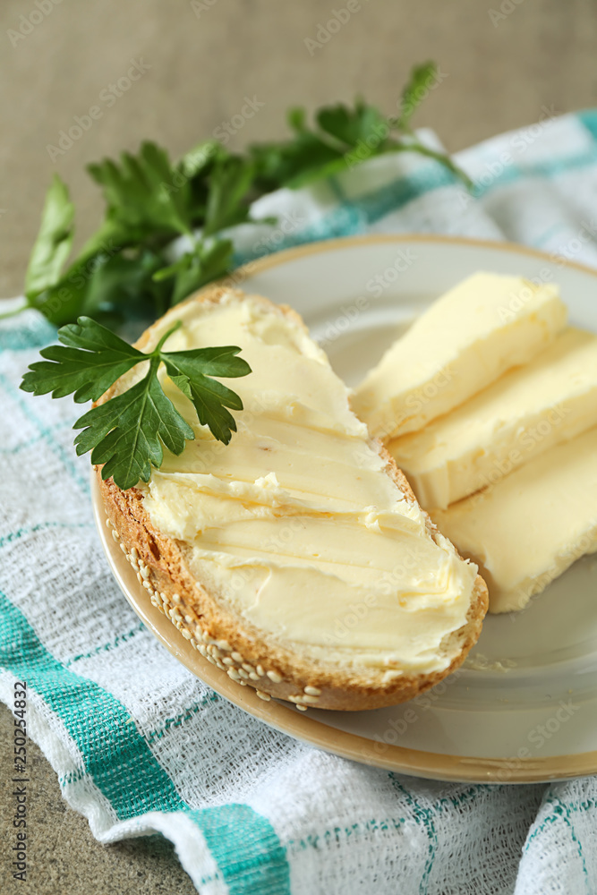 Piece of tasty bread with butter on plate