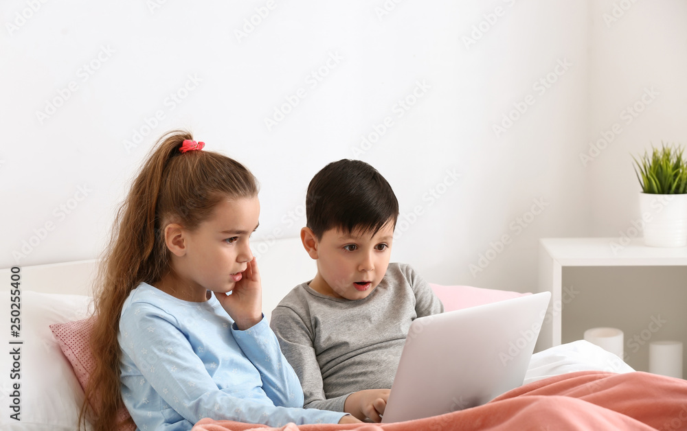 Cute little children with laptop watching cartoons at home