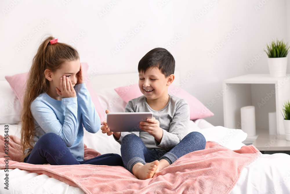 Cute little children with tablet computer watching cartoons at home