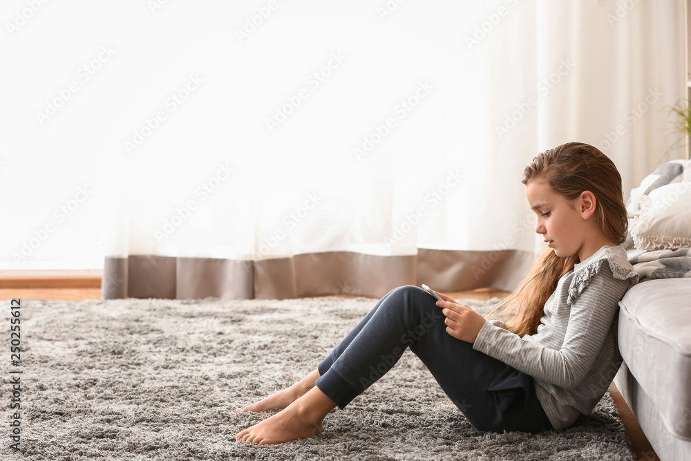 Cute little girl with tablet computer watching cartoons at home