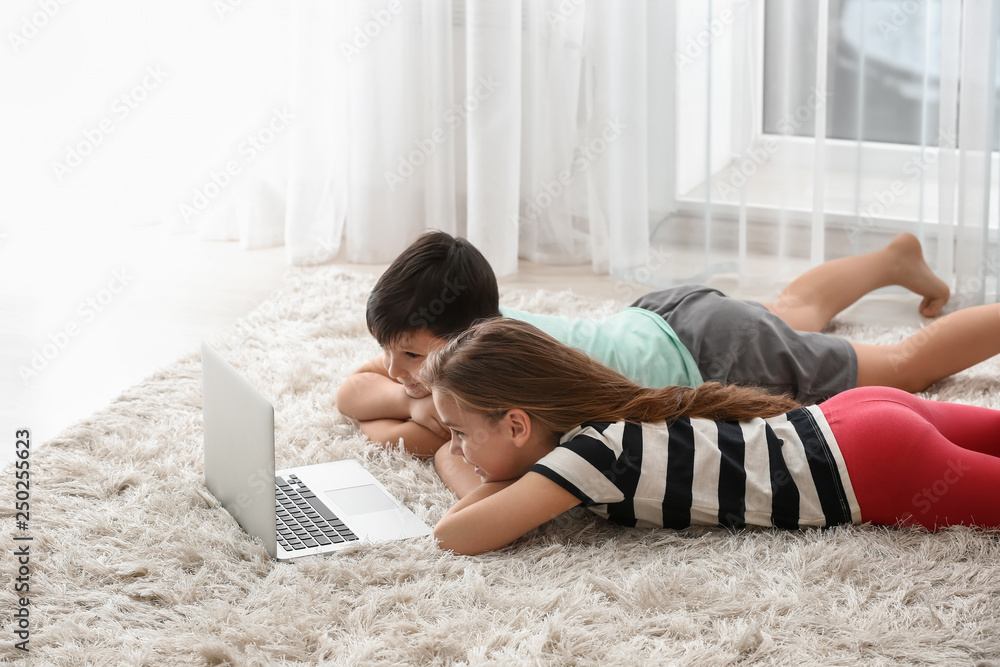 Cute little children with laptop watching cartoons at home