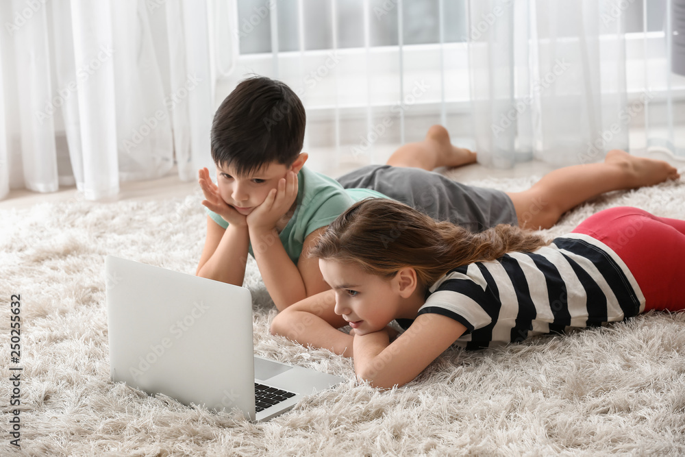 Cute little children with laptop watching cartoons at home