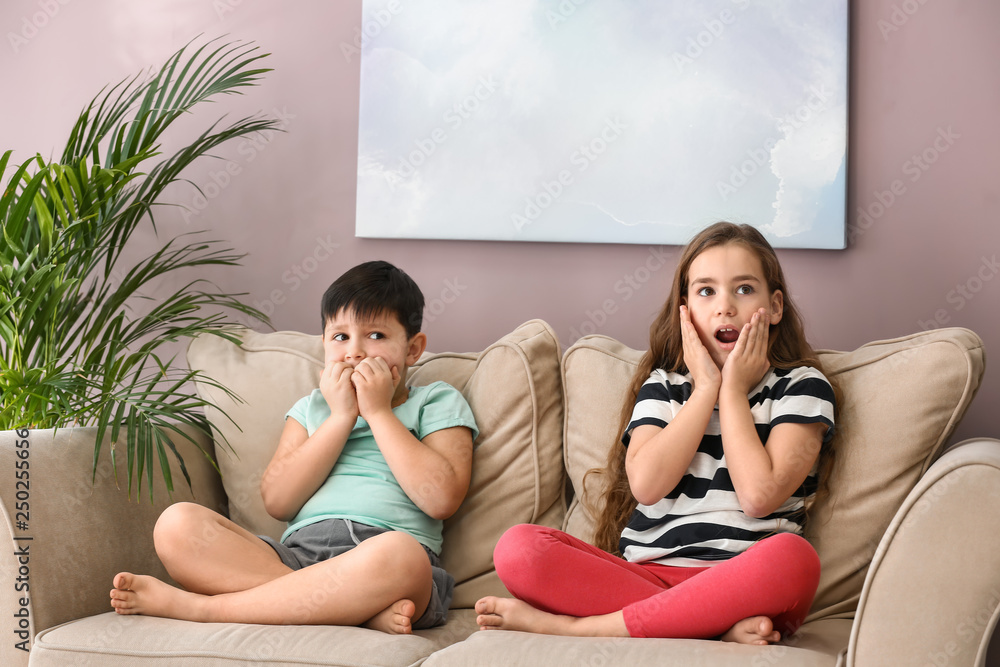 Emotional little children watching cartoons on TV at home