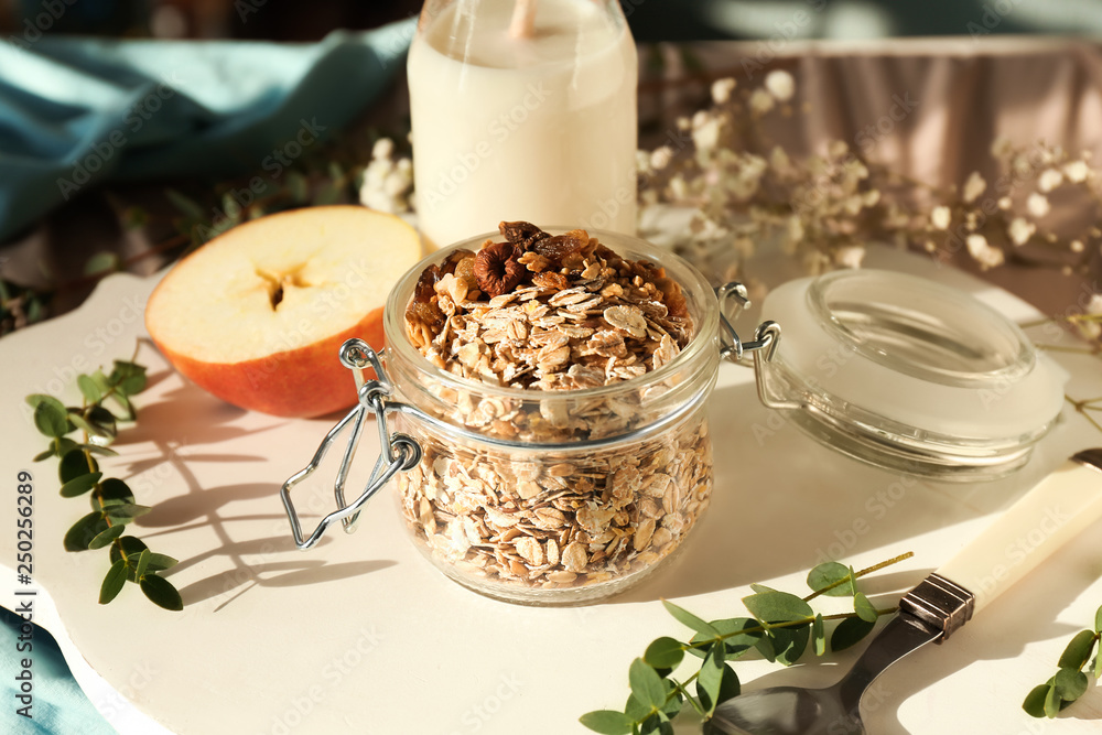 Glass jar with raw oatmeal, bottle of milk and apple on tray