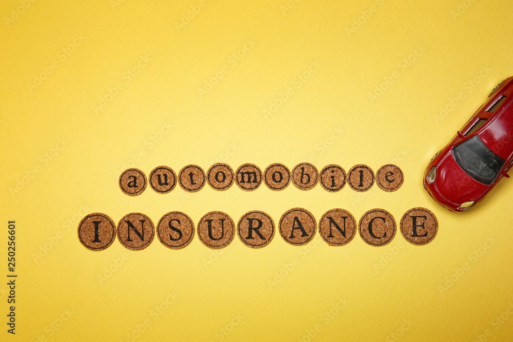 Text AUTOMOBILE INSURANCE with toy car on color background