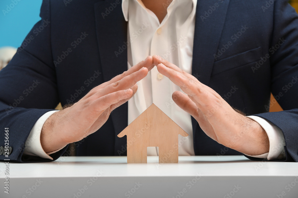 Insurance agent with figure of house sitting at table, closeup