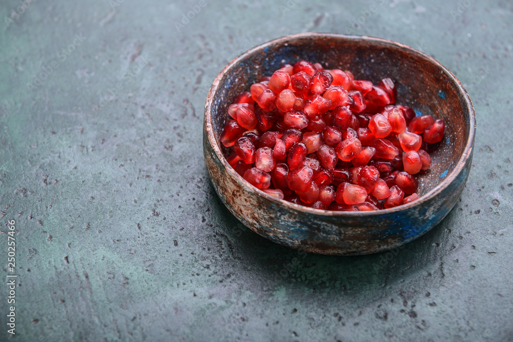 Plate with ripe pomegranate seeds on color background