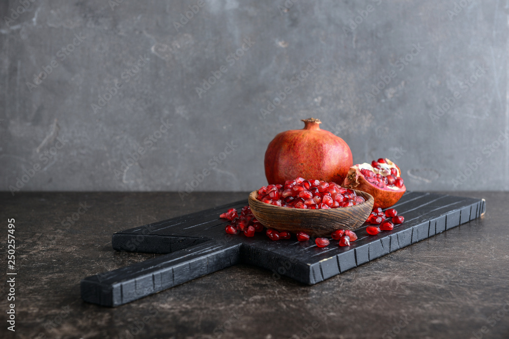 Ripe pomegranate and bowl with seeds on table