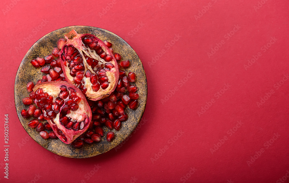 Plate with ripe pomegranates on color background