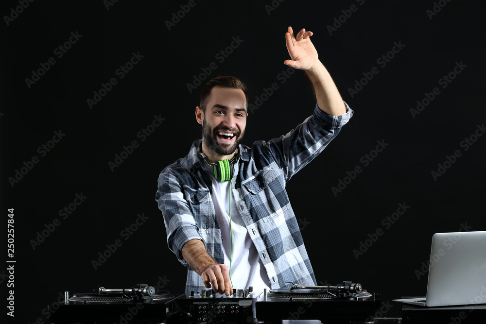 Male DJ playing music on dark background