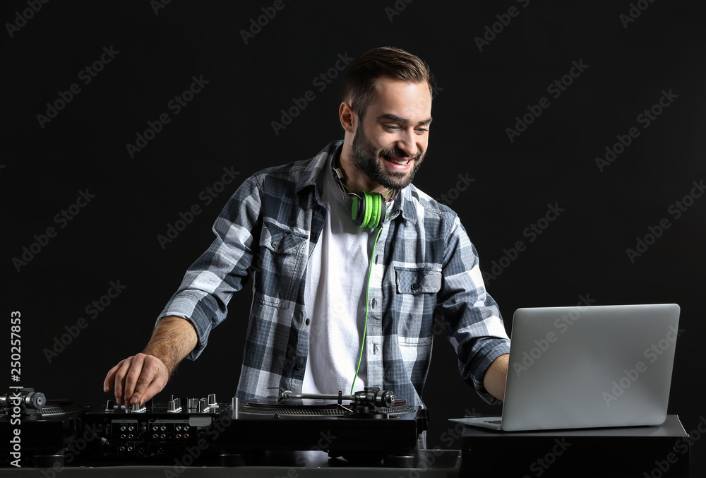 Male DJ playing music on dark background