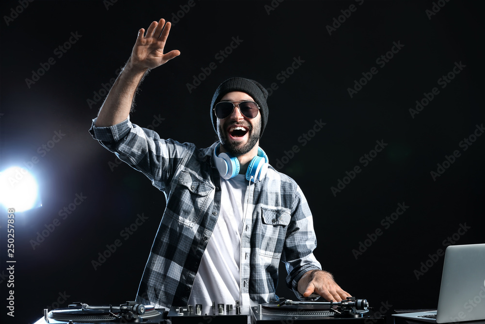 Male DJ playing music on dark background