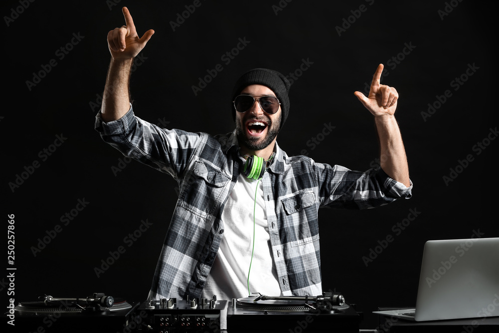 Male DJ playing music on dark background