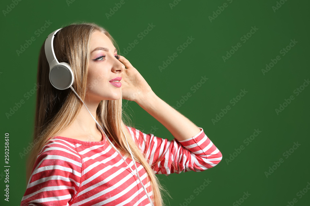 Beautiful young woman listening to music on color background