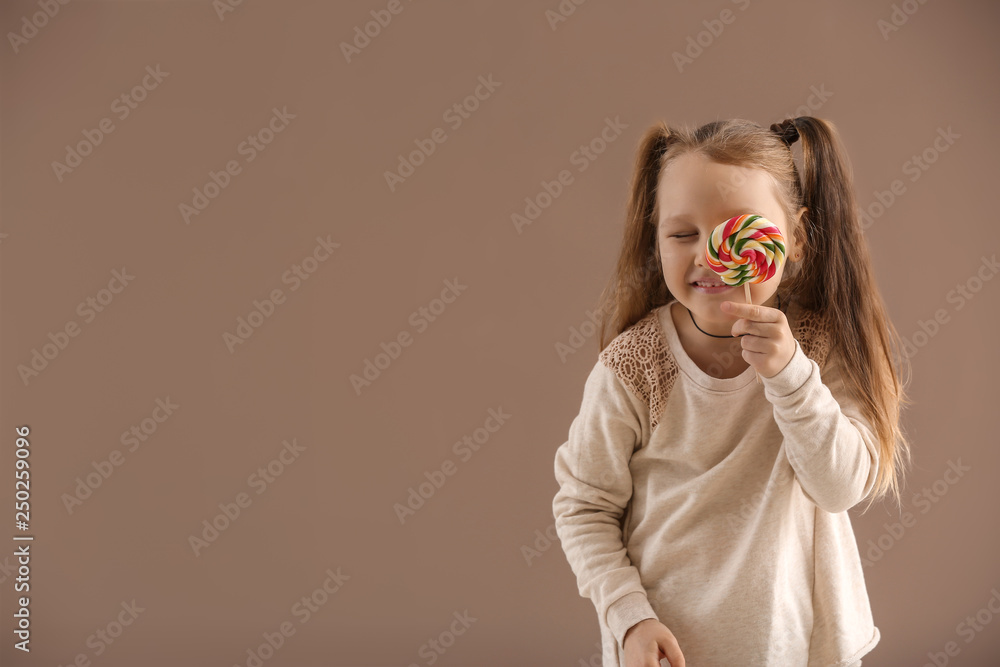 Cute little girl with lollipop on color background