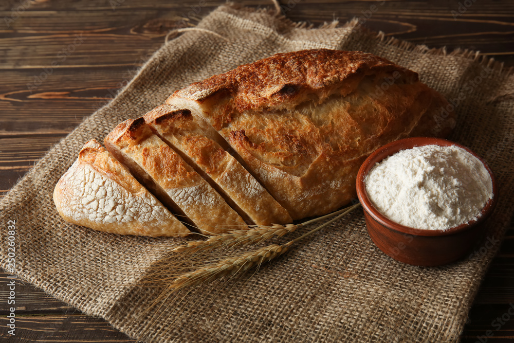 Cut fresh bread on wooden background