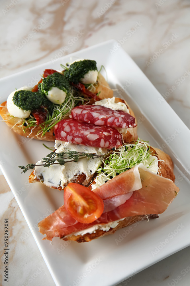 Plate with fresh tasty bruschettas on light background