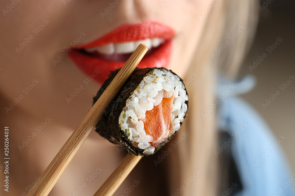 Woman eating tasty sushi roll, closeup